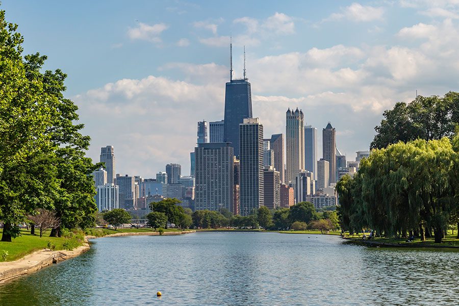 Contact - Panoramic View of Lincoln Park and the Chicago Skyline Displaying Trees on Both Sides of a Lake on a Sunny Day